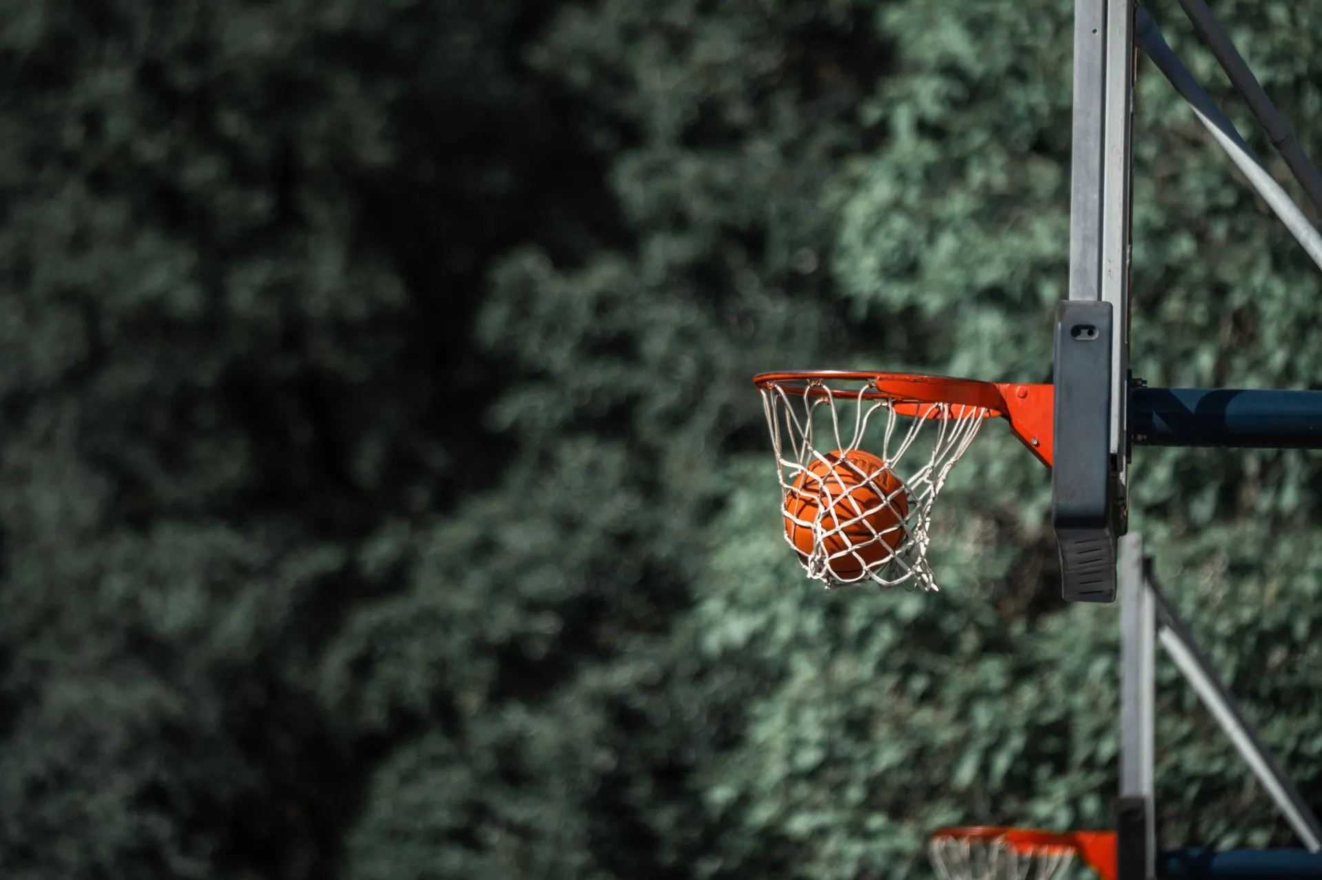 Basketball passing through a white net on an outdoor hoop