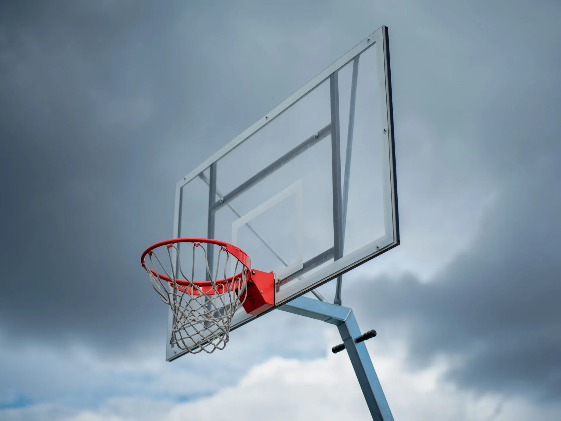 Transparent basketball backboard with a metal frame, orange rim and white net