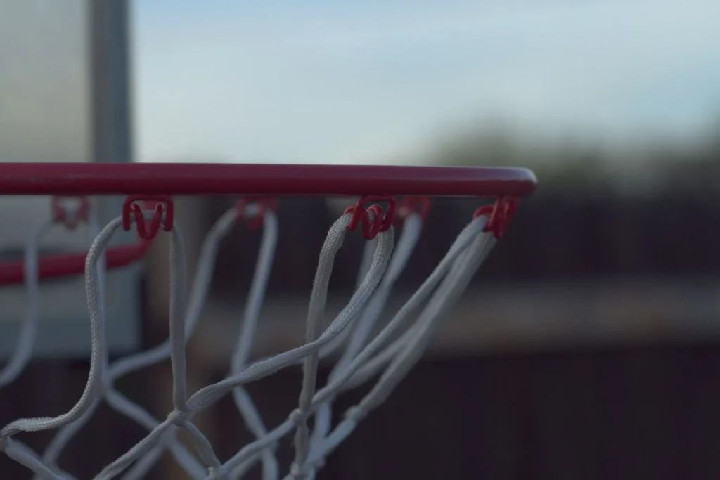 Close-up of a white basketball net attached to red rim hooks