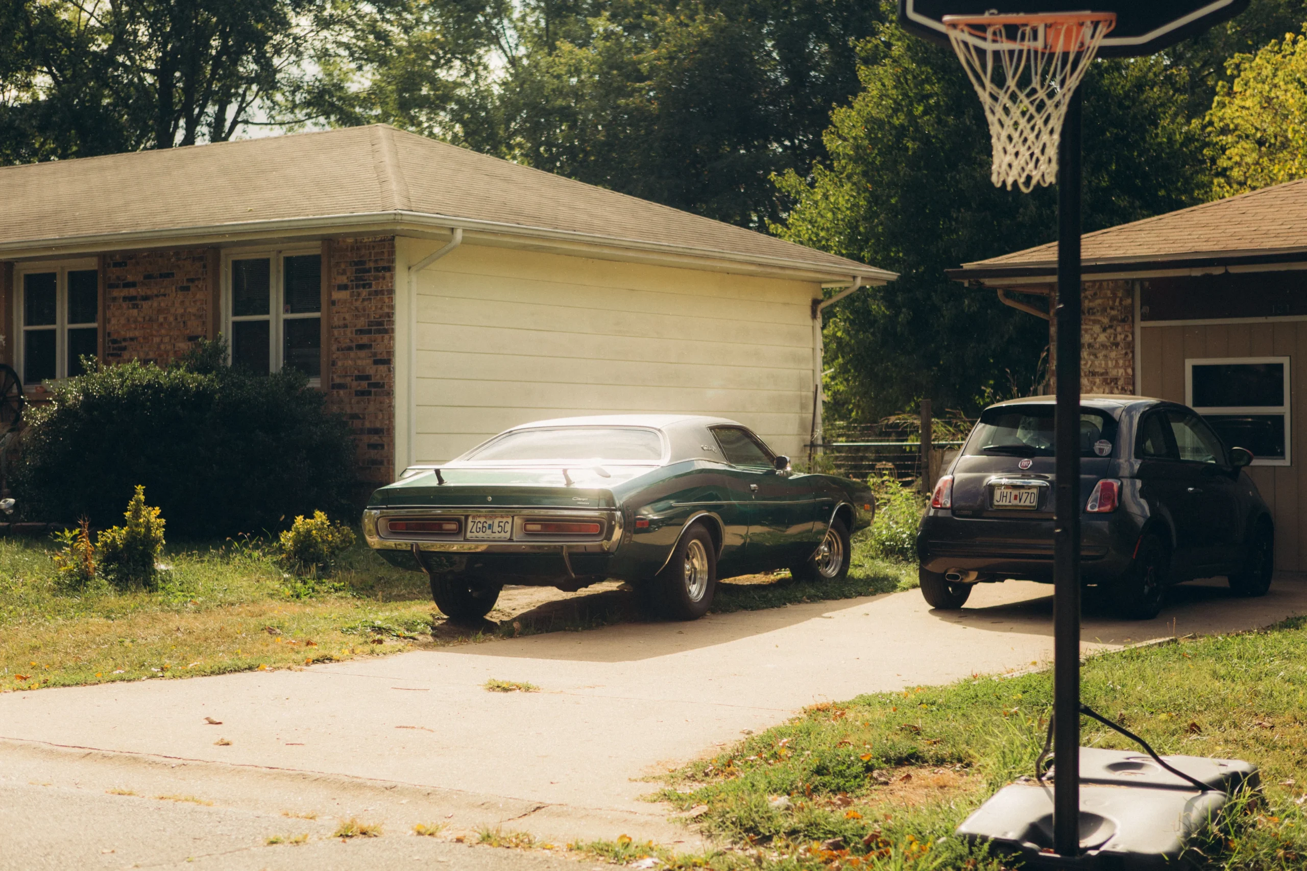 Portable basketball hoop with weighted base beside a residential driveway
